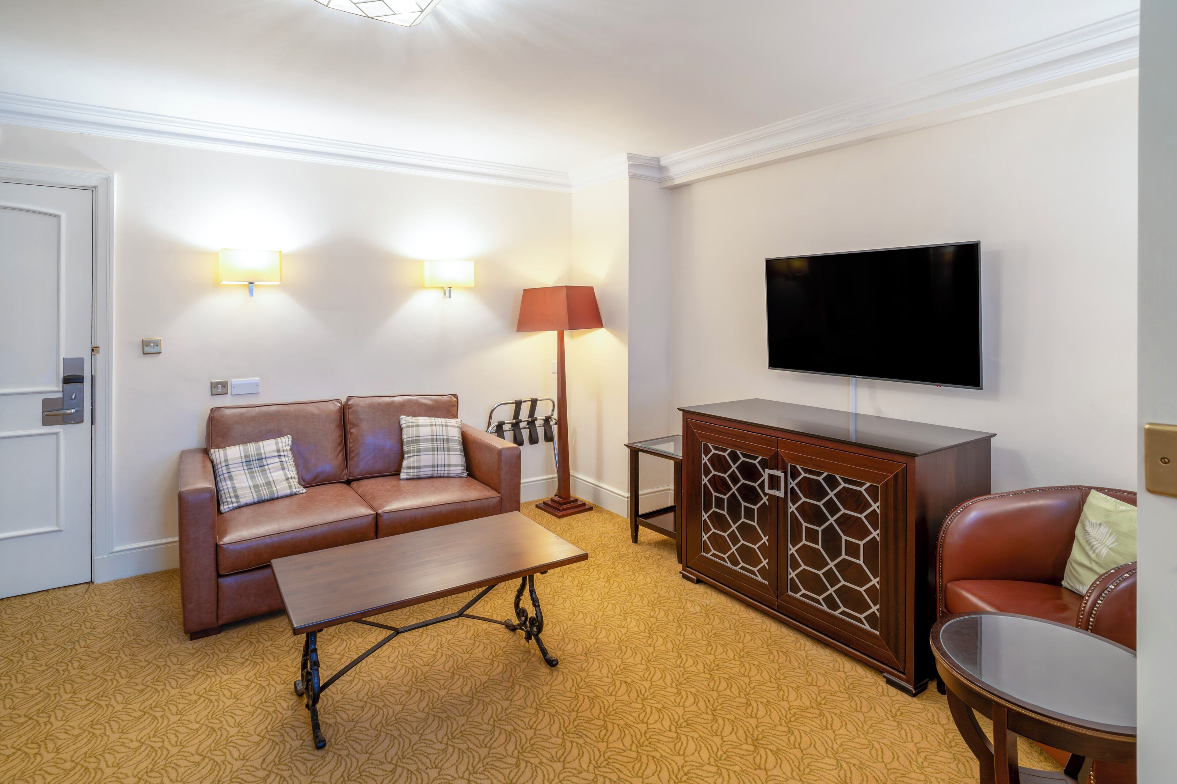 A living room with a sofa, a coffee table, a TV, a lamp, and a cabinet.