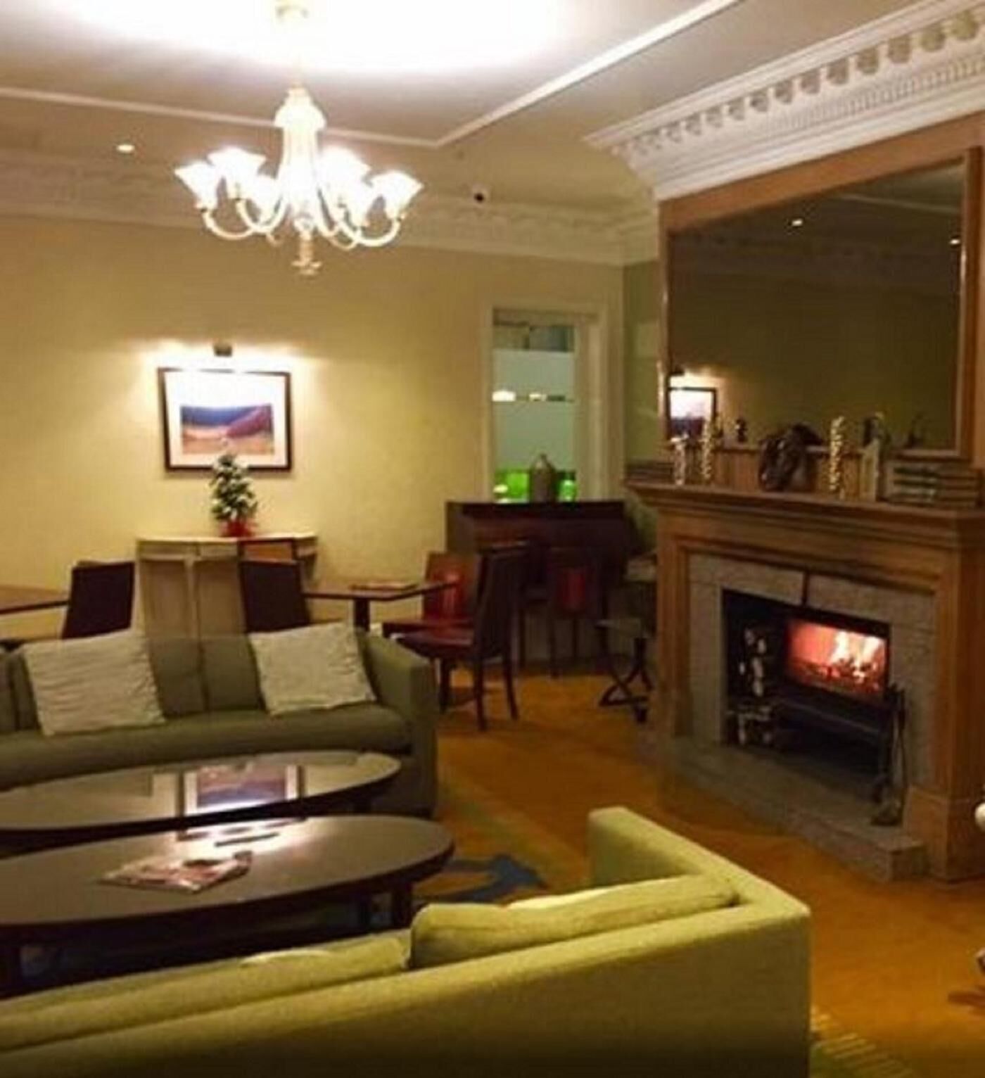 Una sala de estar con un sofá verde, una mesa de centro, una chimenea y un candelabro.