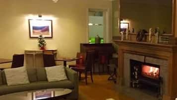 Una sala de estar con un sofá verde, una mesa de centro, una chimenea y un candelabro.