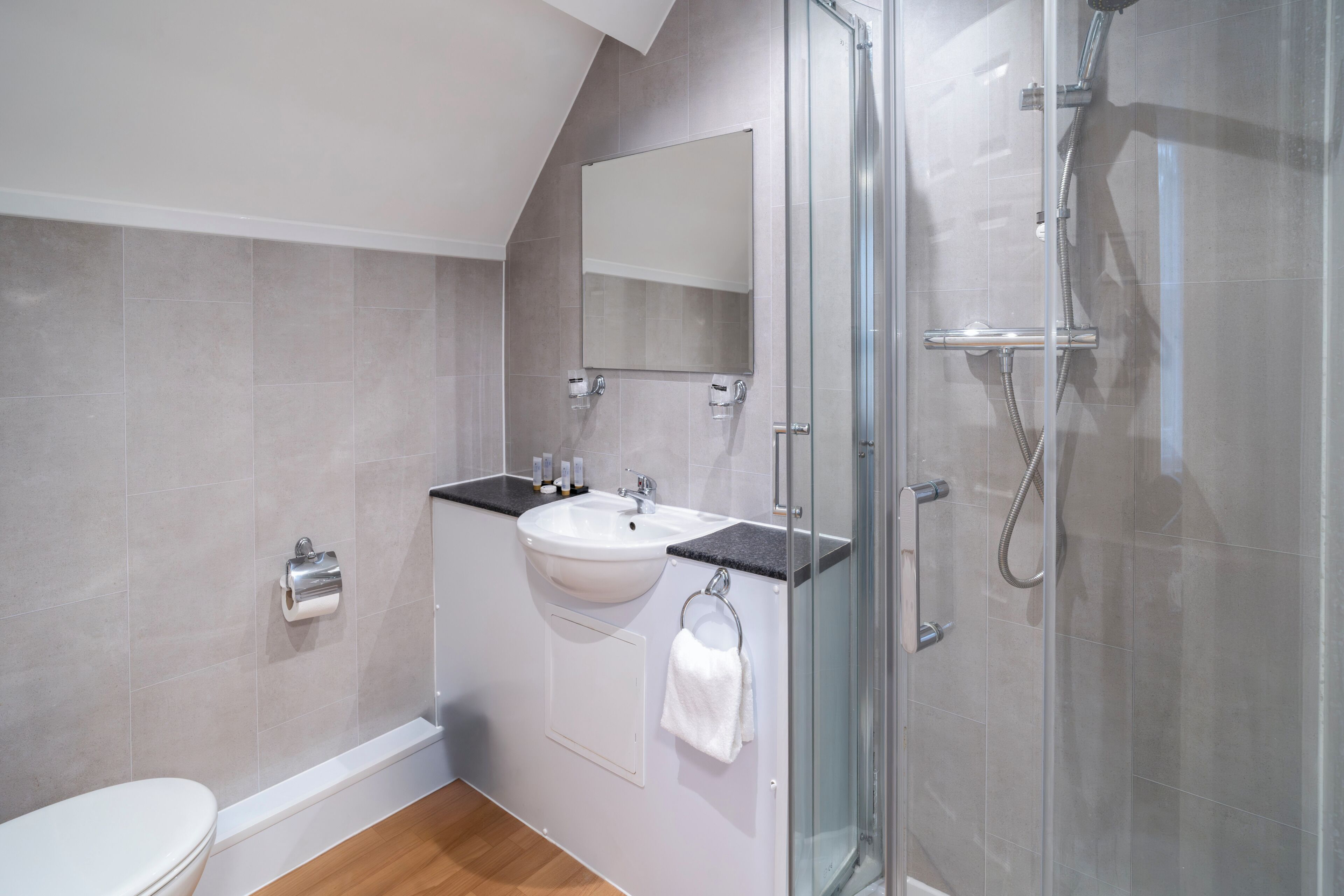 Une salle de bain moderne avec une douche à parois de verre, un lavabo blanc et un miroir au-dessus.