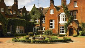 A traditional brick building with ivy-covered walls, a central fountain, and a well-maintained garden. - Sprowston Manor Hotel, Spa & Golf (Norwich)
