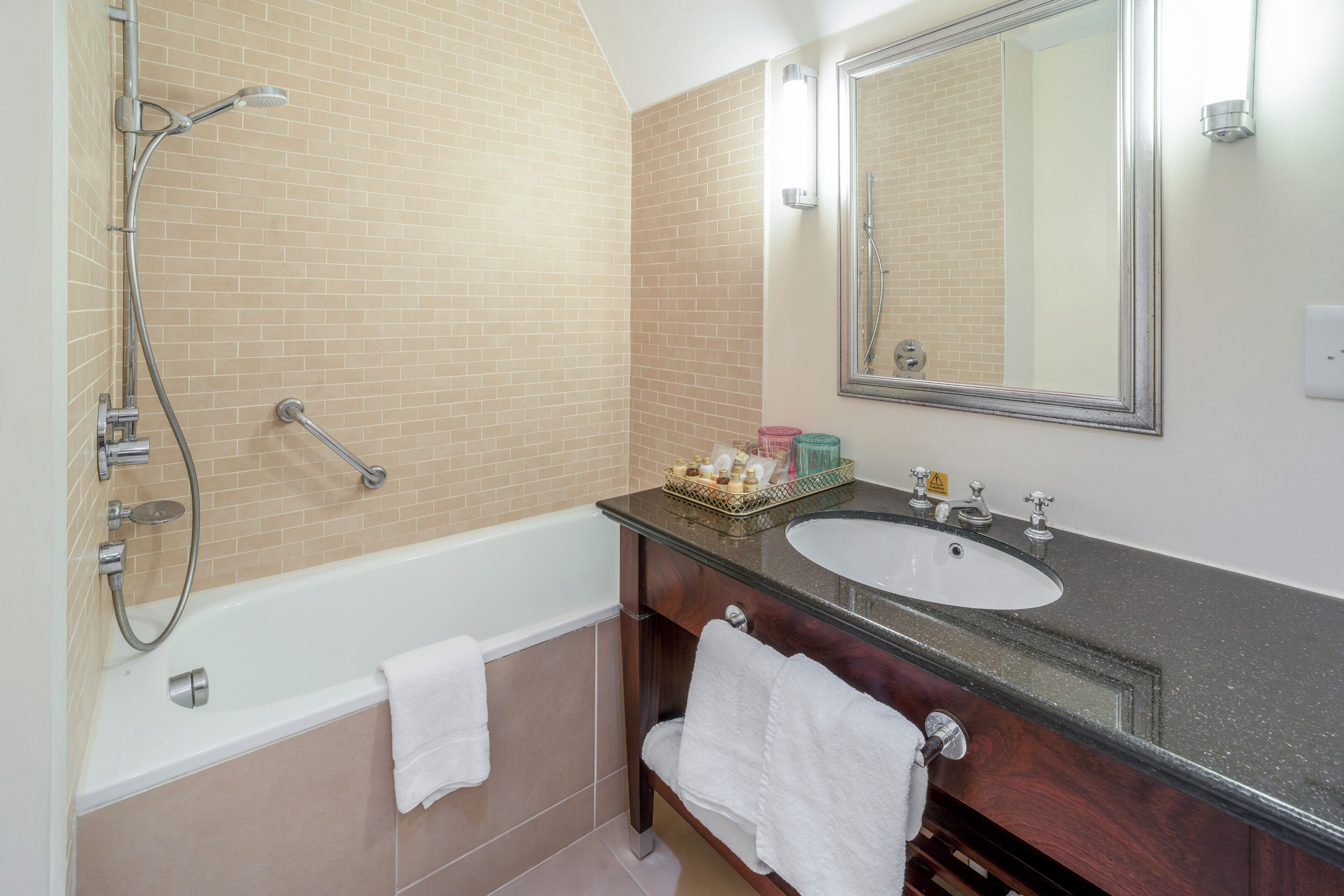 A bathroom with a bathtub, a sink, a mirror, and a shower.
