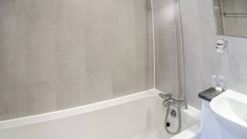 A bathroom with a bathtub, shower, and sink.