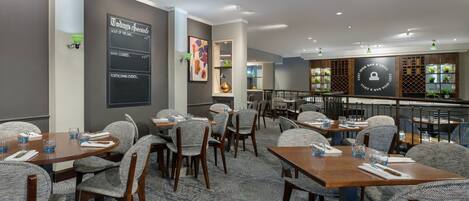 A restaurant with tables and chairs, a menu board, and a bar area.