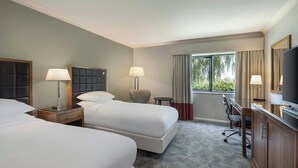 A hotel room with two beds, a desk, a chair, a TV, and a window with curtains. - Delta Hotels by Marriott Northampton (Northampton)