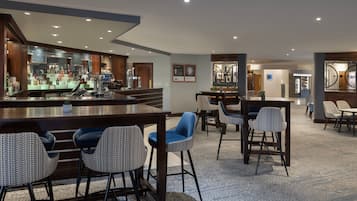 A modern bar area with a counter, stools, and a seating area with chairs.