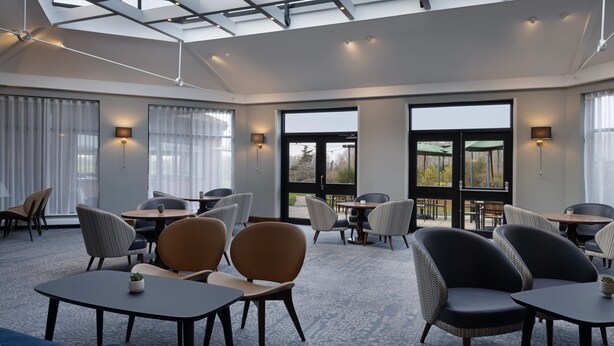 A modern hotel lobby with multiple seating areas, large windows, and a skylight. - Delta Hotels by Marriott Northampton (Northampton)