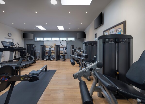 A spacious gym with various exercise equipment, including treadmills, weight machines, and a rowing machine.
