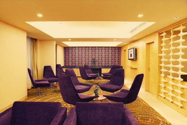 A hotel room with purple chairs arranged around a small table, a patterned wall, and a decorative white partition. - The Metropolitan Hotel and Spa New Delhi (New Delhi)