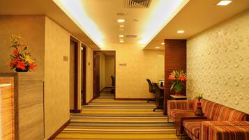 A hotel lobby with a striped carpet, a reception desk, a sofa, and a wall with circular patterns.