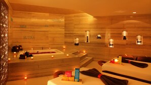 A spa room with a wooden wall, a bathtub, and a massage table.