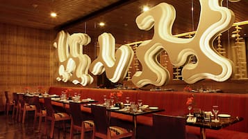 Un restaurante con paredes de paneles de madera, asientos tapizados en rojo y mesas dispuestas para comer.