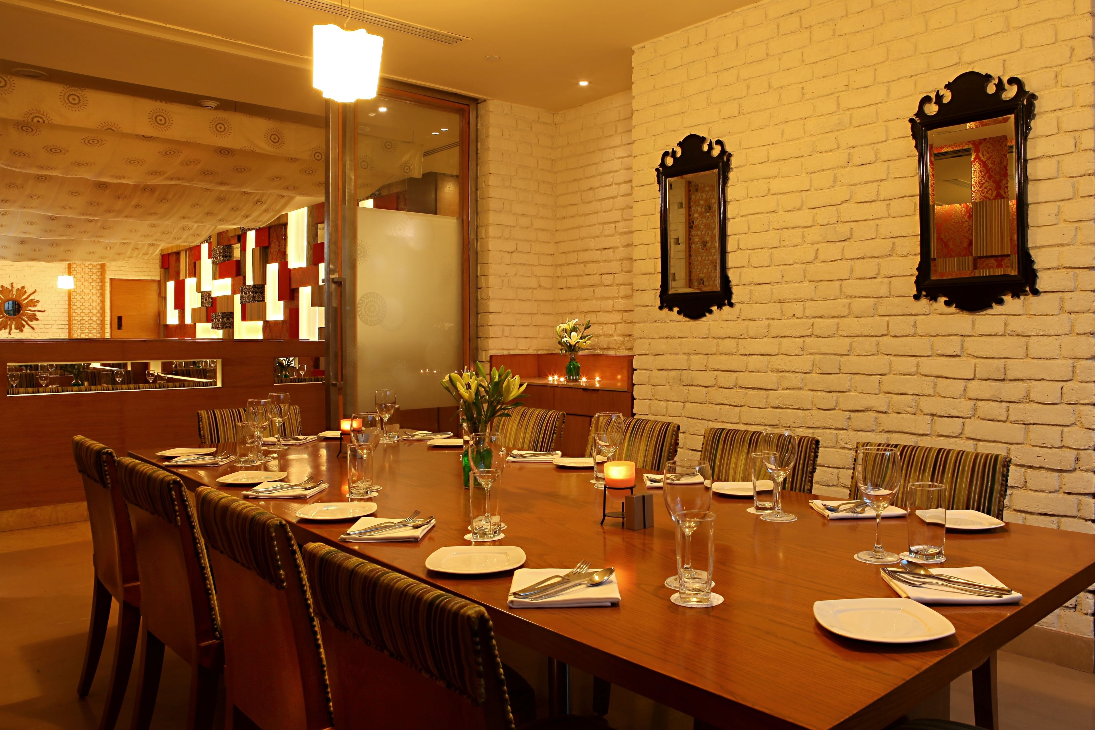 A dining area with a long wooden table set for a meal, surrounded by upholstered chairs.