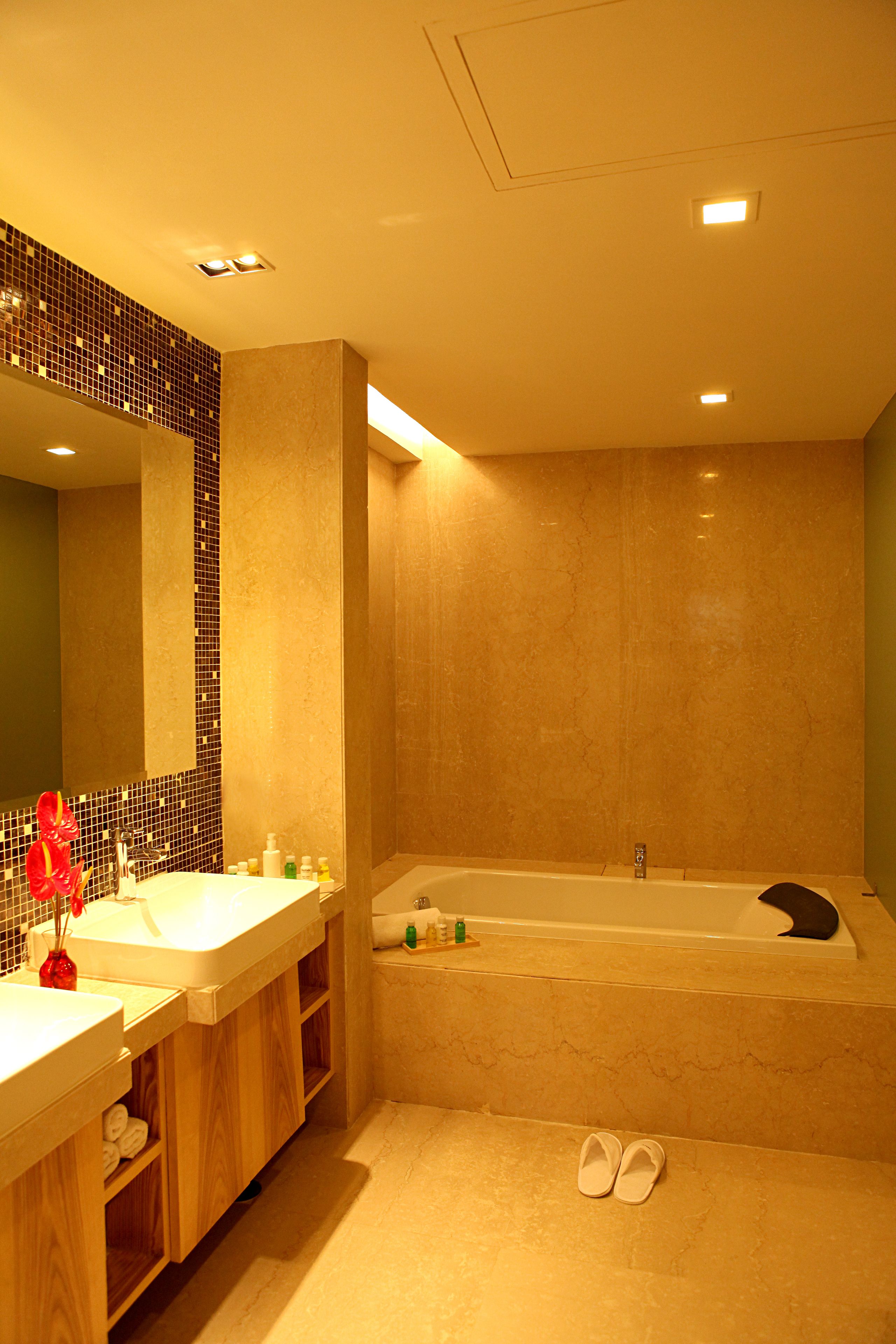A bathroom with a large bathtub, a sink with a mirror, and a wooden vanity.
