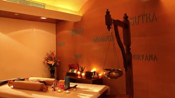 Una habitación con una cama, una balanza y una pared donde se leen las palabras "MIMANSA" y "NIRVANA".