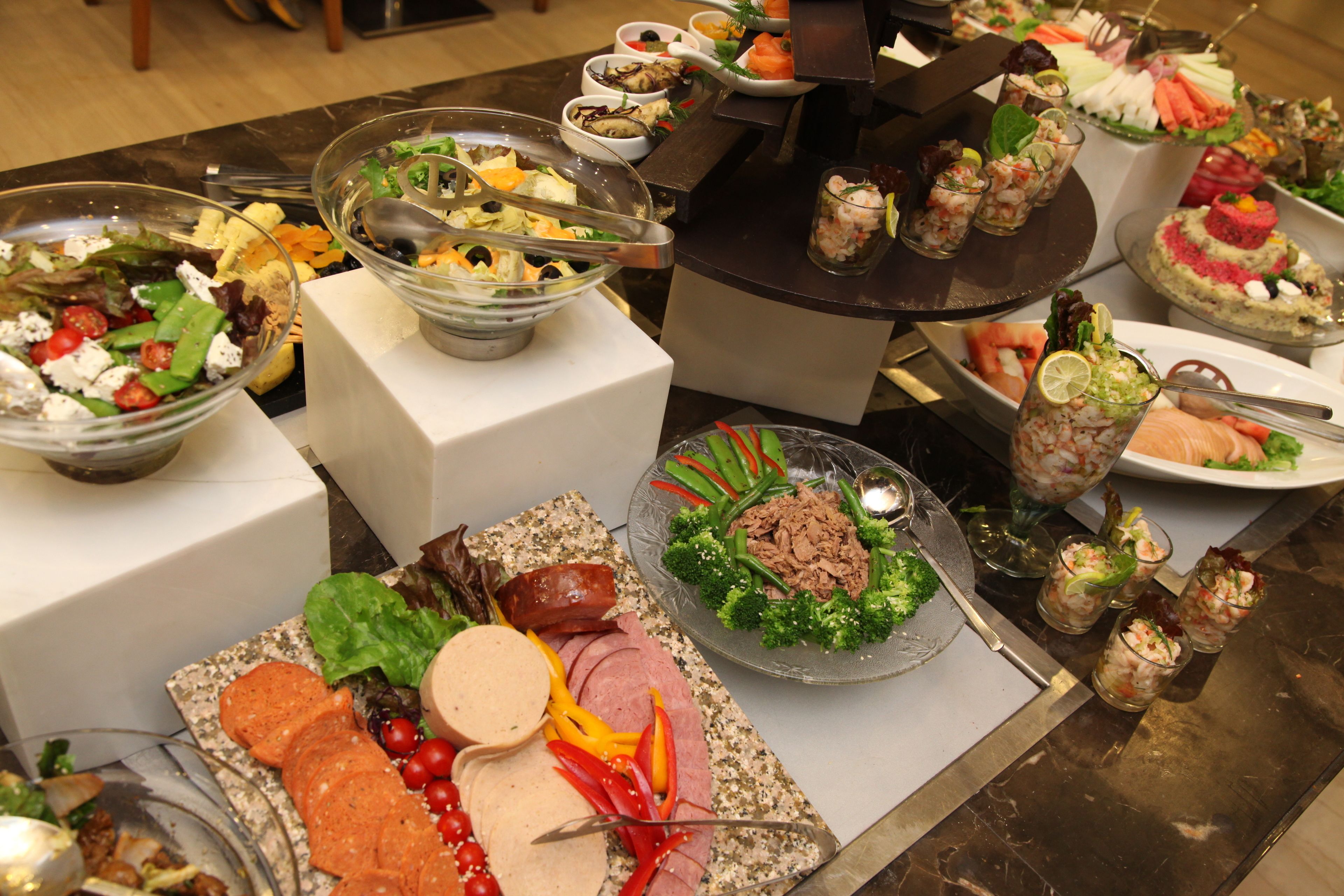 A buffet with various food items including salads, meats, and seafood.