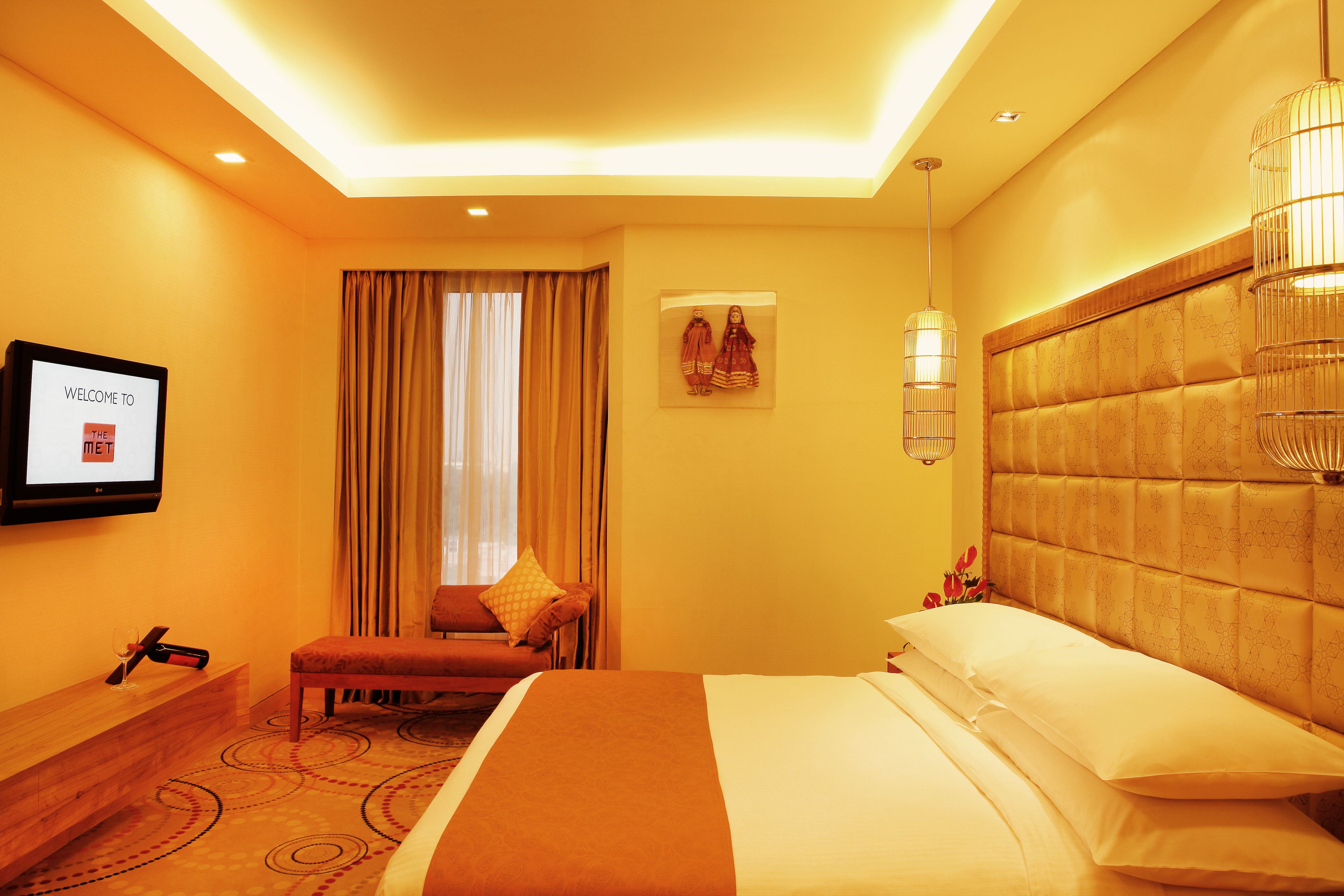 A hotel room with a bed, a television, a sofa, and a window with curtains.