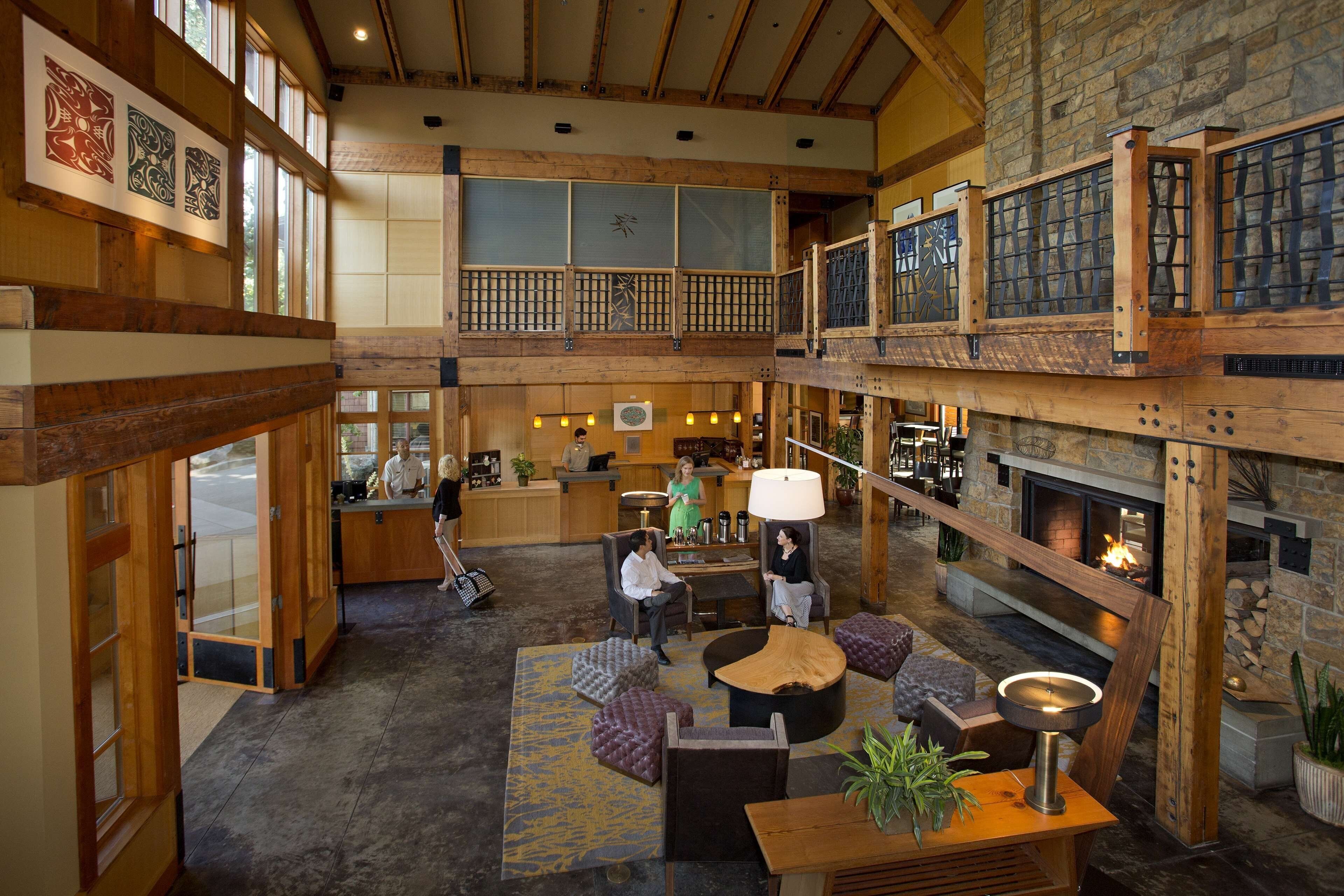 A spacious lobby with a high ceiling, wooden beams, a fireplace, and a reception desk.