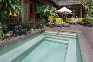 A swimming pool with a tiled edge, surrounded by greenery and outdoor furniture. - Willows Lodge (Woodinville)