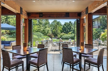 A conference room with multiple round tables, chairs, a projector screen, and a fireplace. at Willows Lodge