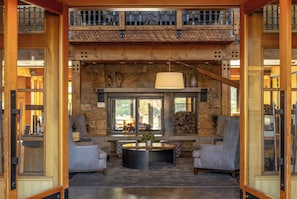 Un hall amplio con pared de piedra, chimenea y vistas al exterior.