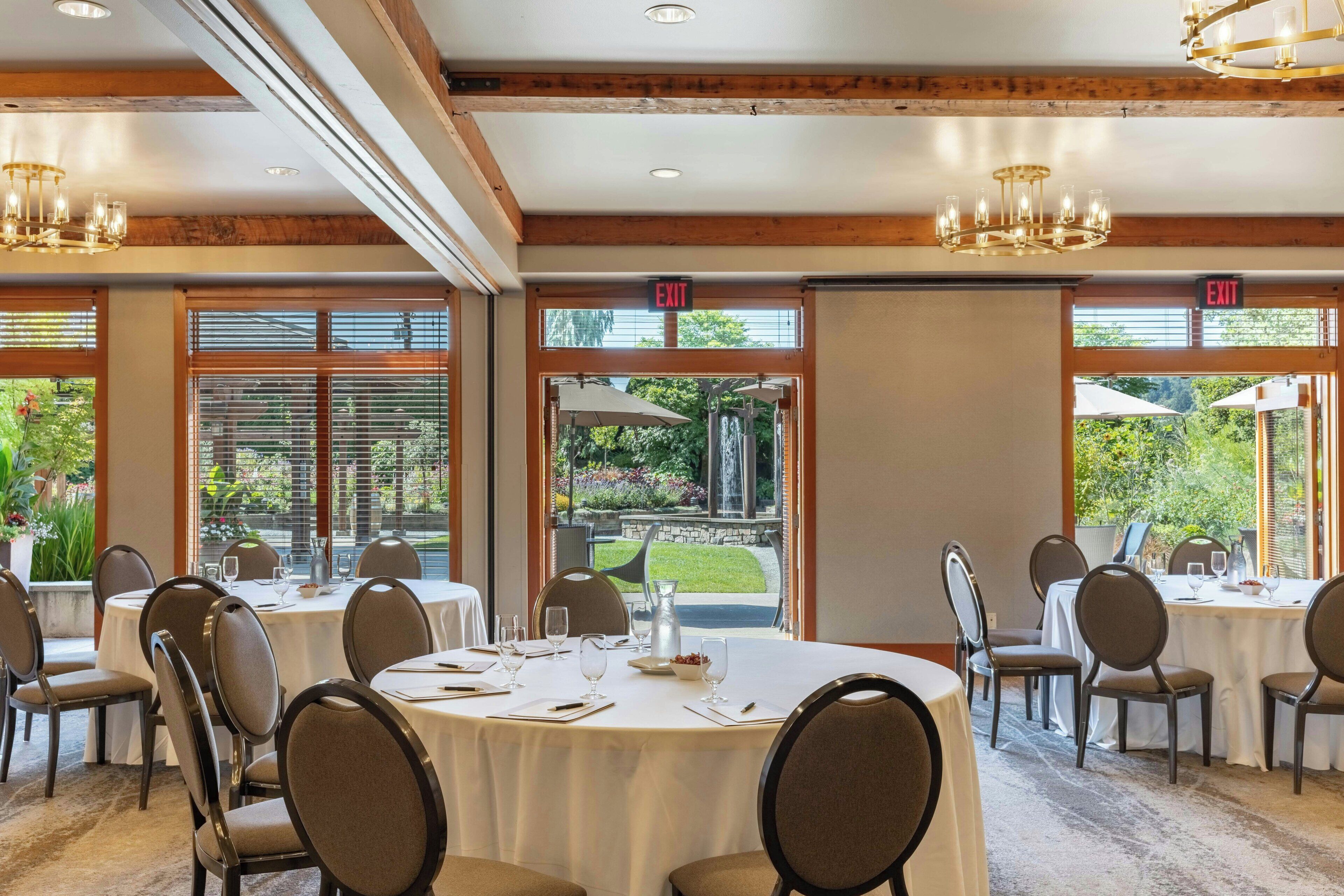 A dining area with round tables, chairs, and exit signs.
