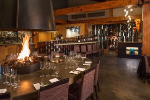 Zona de bar con chimenea, botellas de vino y asientos.