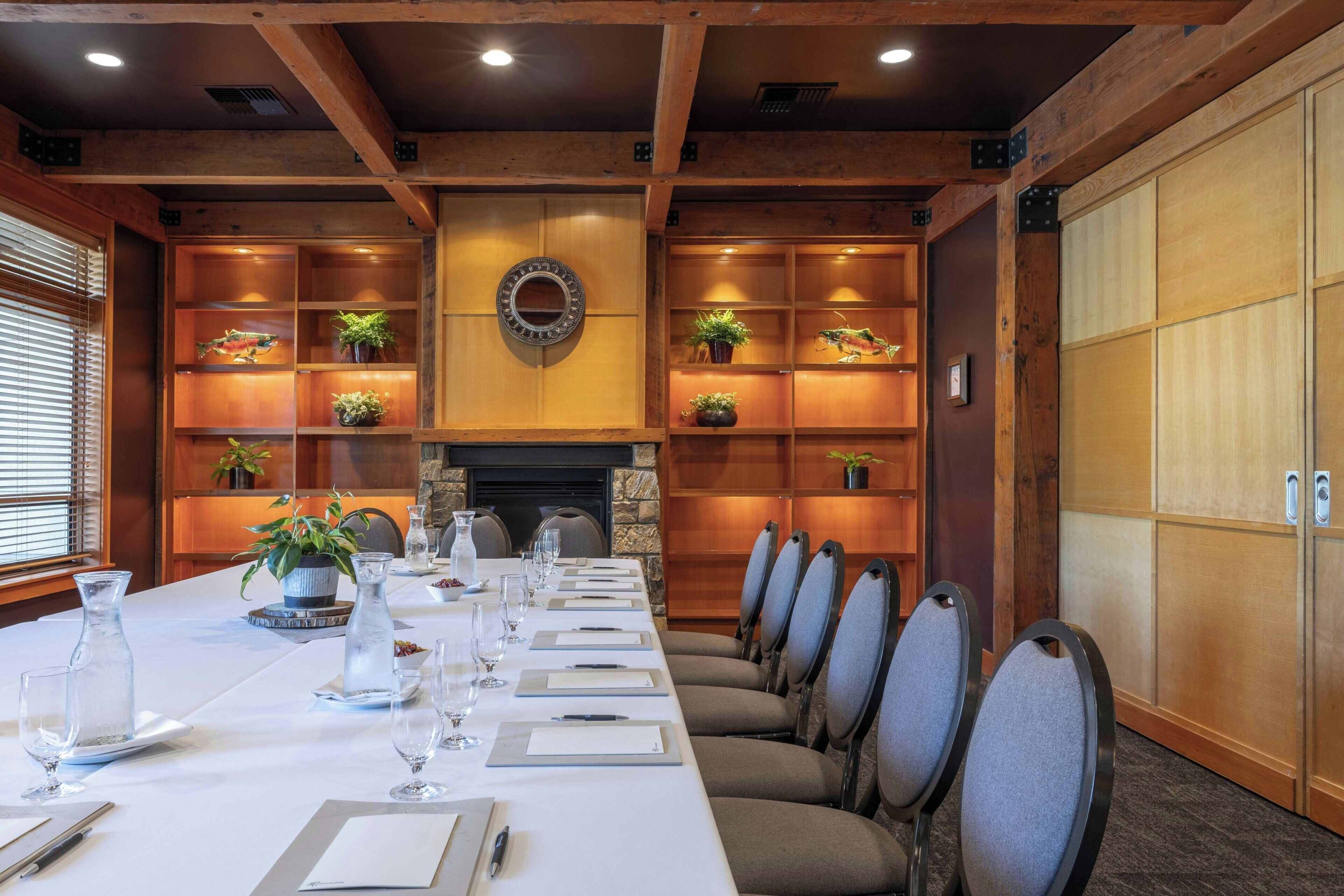 A conference room with a long table, chairs, and shelves with plants.