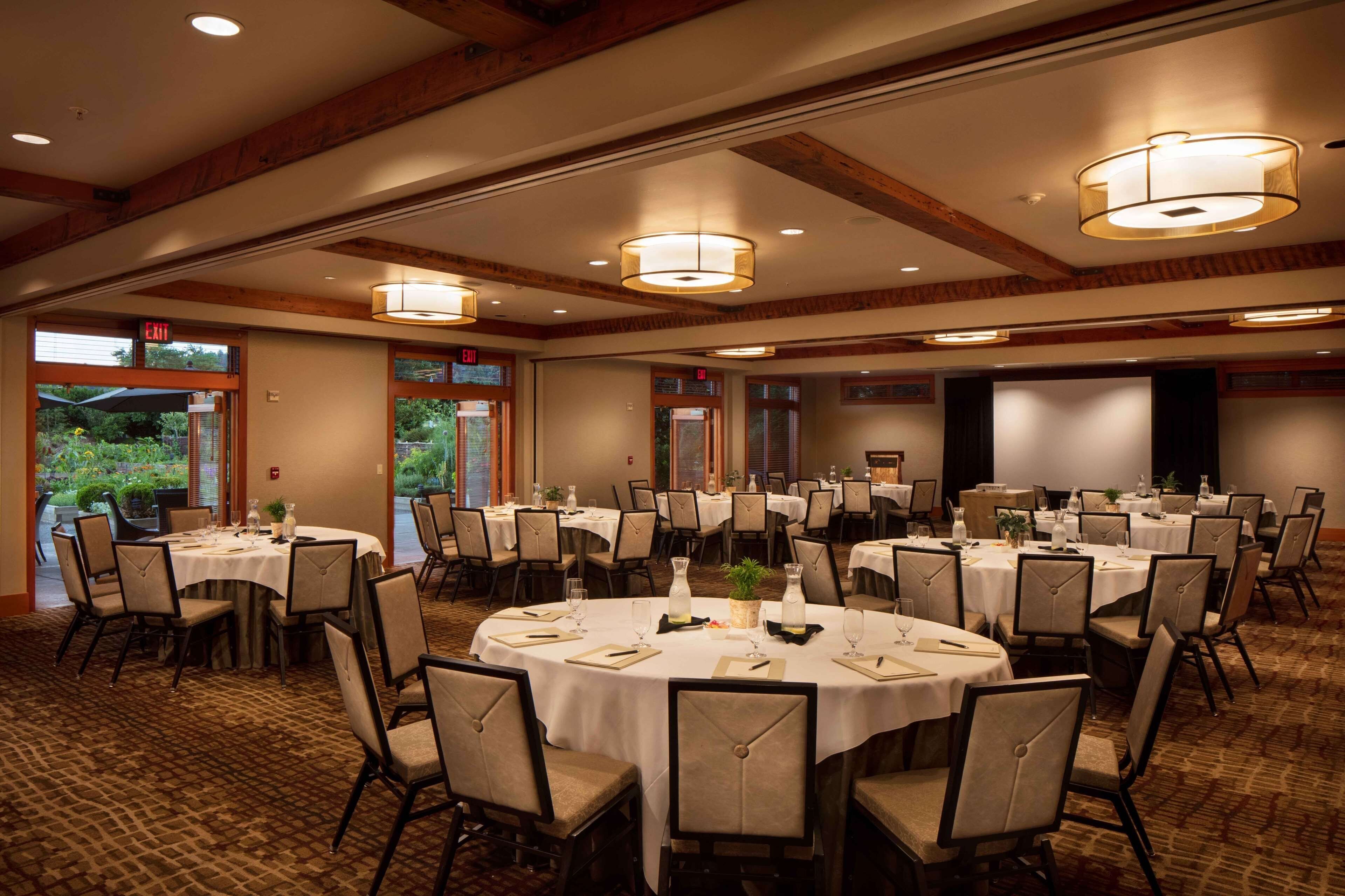 A conference room with multiple round tables, chairs, and ceiling lights.