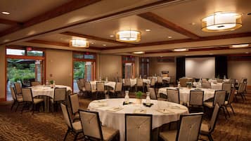 A conference room with multiple round tables, chairs, and ceiling lights.