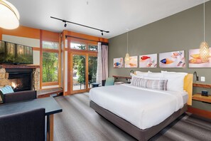 A hotel room with a large bed, a fireplace, a television, and artwork on the walls. - Willows Lodge (Woodinville)
