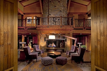 A hotel room with a large bed, a fireplace, a television, and artwork on the walls. at Willows Lodge