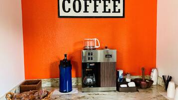 Eine Kaffeestation mit Kaffeemaschine, Wasserspender und einer Kaffeetasse.