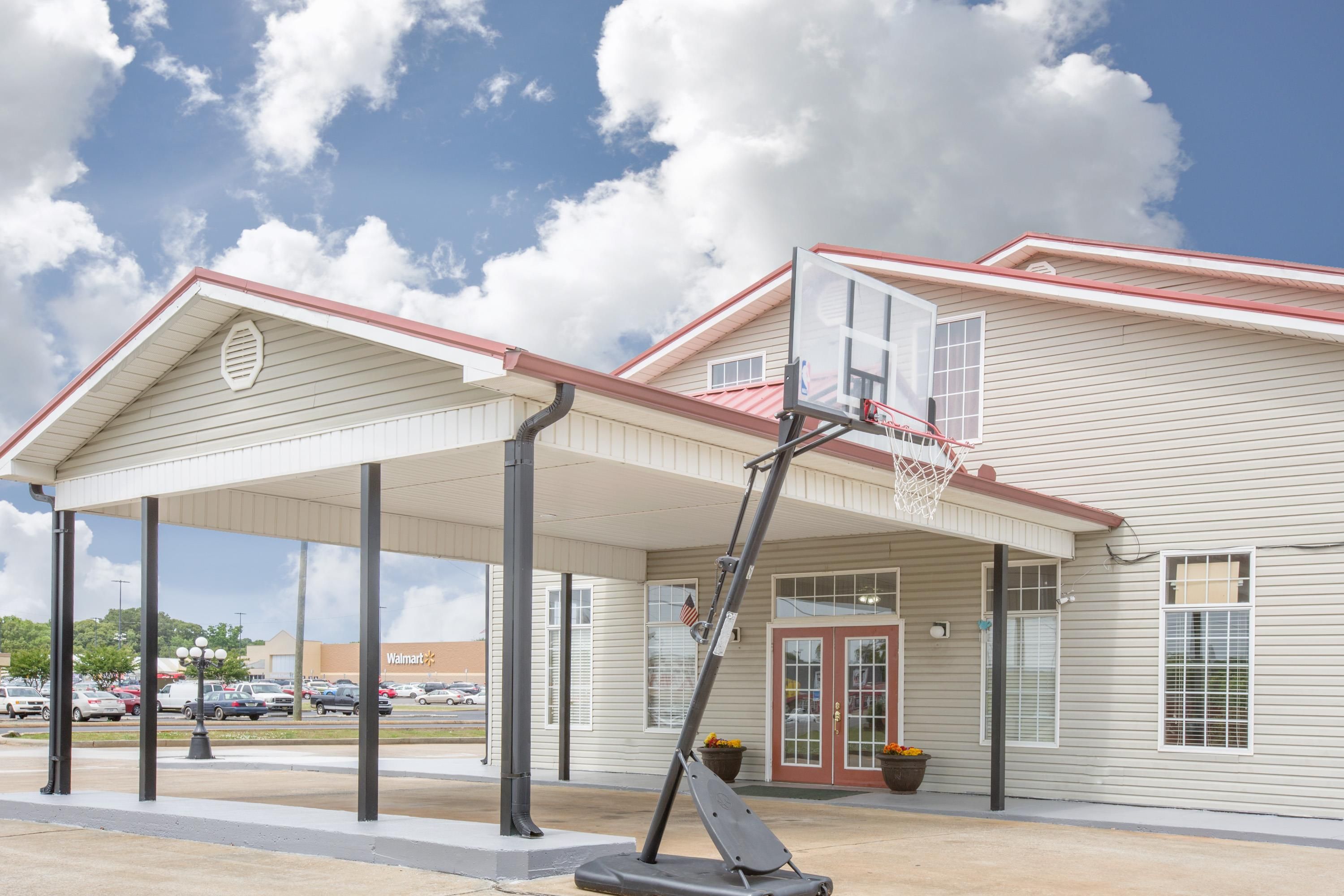 Un bâtiment doté d’une entrée couverte, d’un panier de basketball et d’une enseigne Walmart.