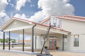 Un edificio con vestíbulo cubierto, canasta de baloncesto y cartel de Walmart.