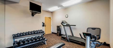 Ein Fitnessraum mit Laufband, Ergometer, Hanteln und einer Trainingsbank.