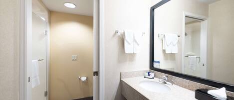 Une salle de bain d’hôtel avec un lavabo, un miroir et un porte-serviettes.