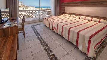 Una habitación de hotel con cama, escritorio y vista al mar.