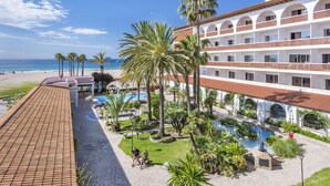 A resort with a pool, palm trees, and a beach view. - 4R Gran Europe (El Vendrell)