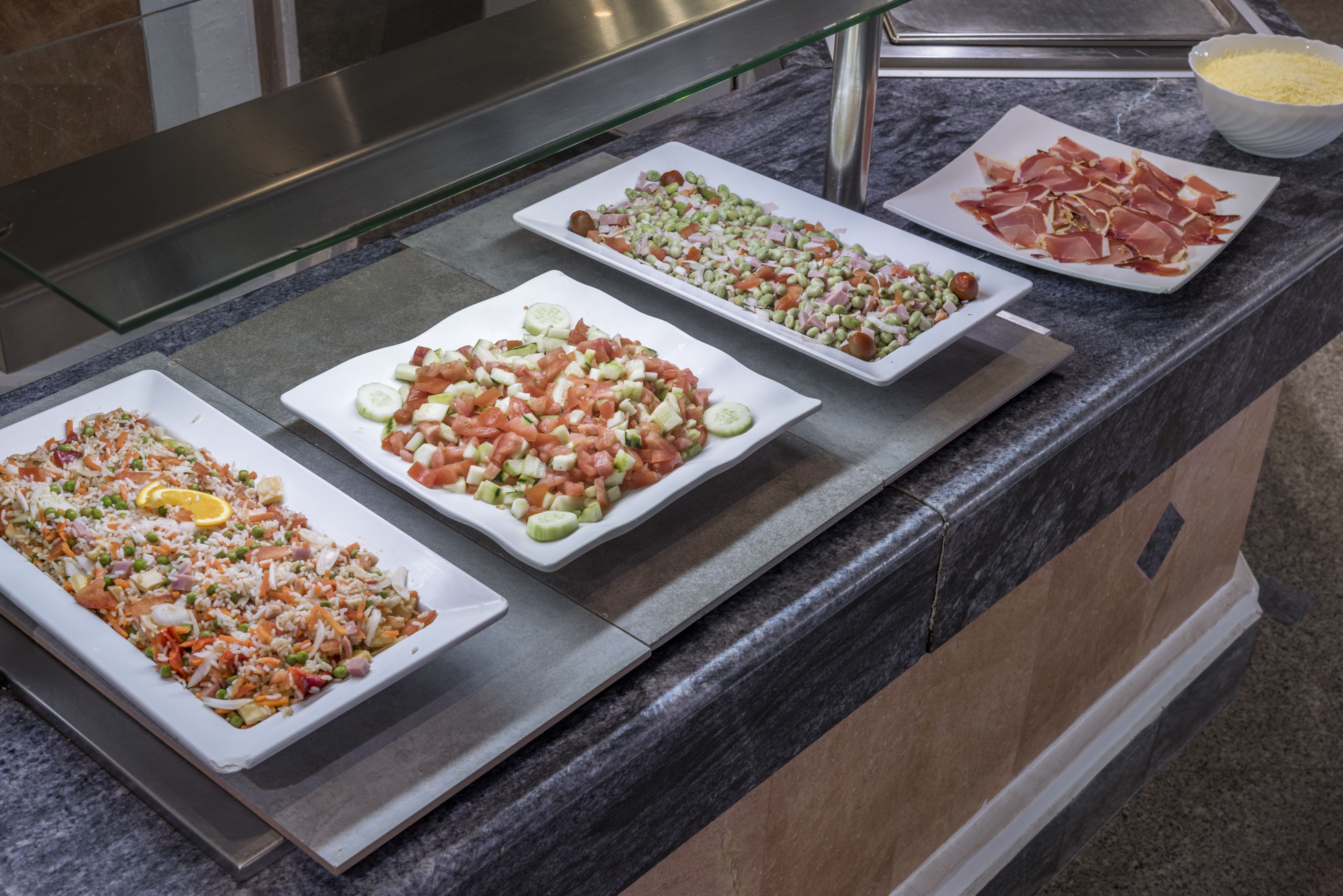 Een buffet met diverse gerechten, waaronder salades, vleeswaren en garneringen.