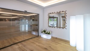 A modern interior with a glass partition, a white planter with flowers, and a large mirror with an ornate frame. - 4R Gran Europe (El Vendrell)