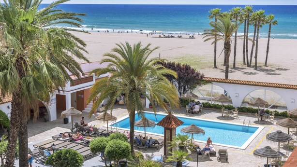 A pool area with lounge chairs, a swimming pool, and a view of the beach and ocean. - 4R Gran Europe (El Vendrell)