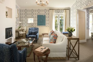 A living room with a fireplace, a sofa, a coffee table, and patterned wallpaper.