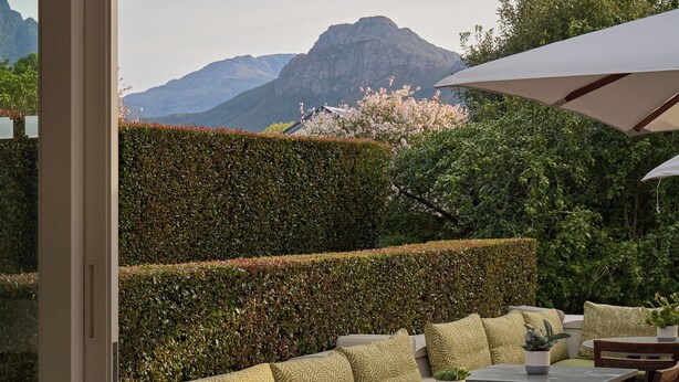 Ein Außenbereich mit Tischen, Stühlen und einer Couch, mit Blick auf Berge.