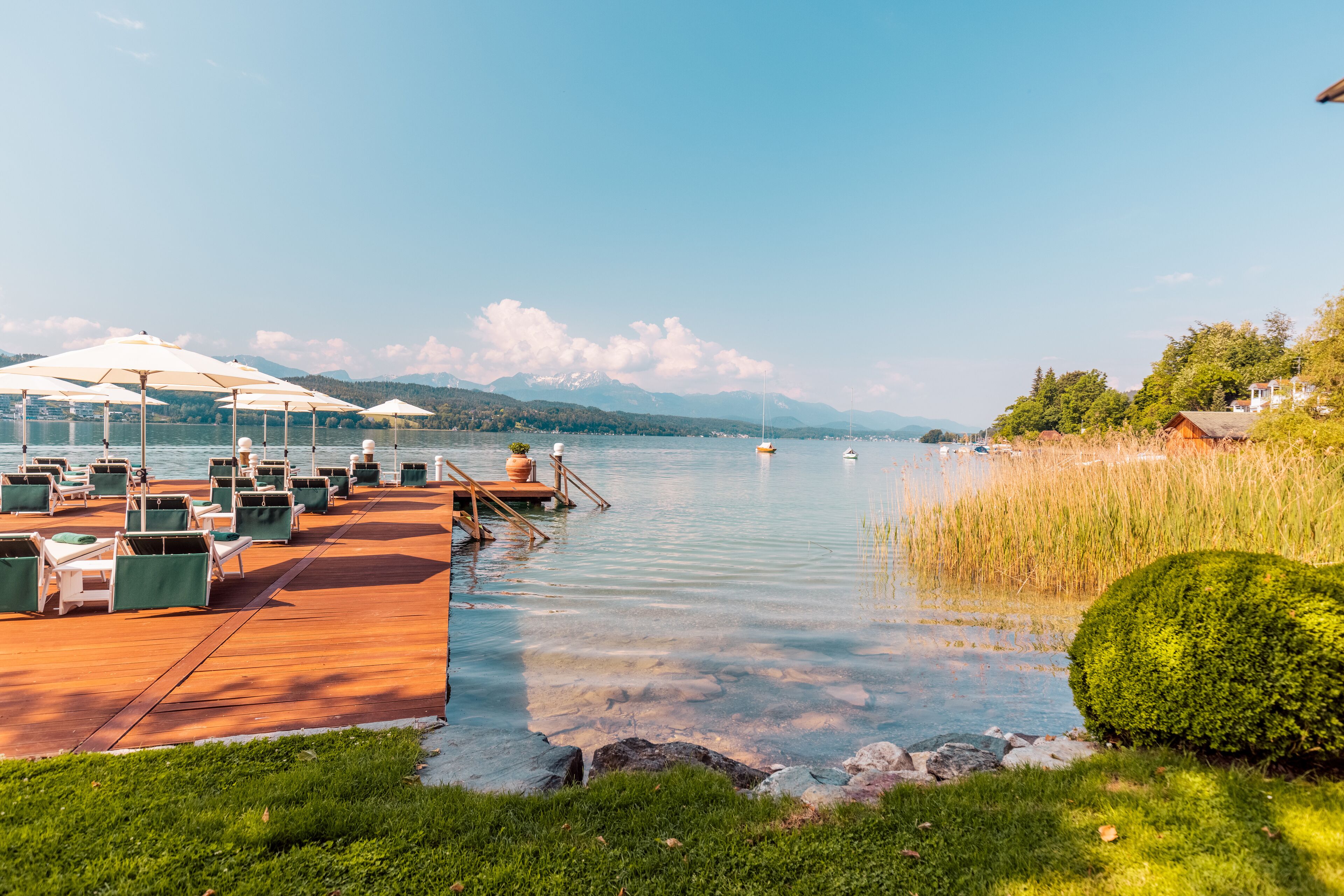 Une terrasse au bord du lac, dotée de sièges extérieurs et offrant une vue sur le lac et les montagnes.