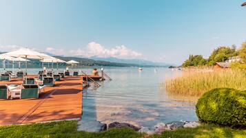 Une terrasse au bord du lac, dotée de sièges extérieurs et offrant une vue sur le lac et les montagnes.