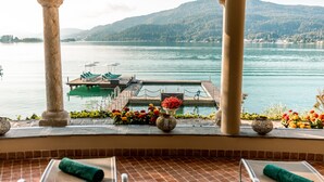 Una terraza con vistas a un lago, un muelle con sillones de descanso y un arreglo floral.