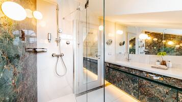 A modern bathroom with a glass shower enclosure, a marble countertop, and a large mirror.