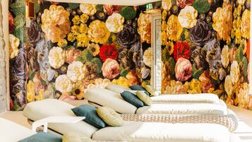 A room with a bed, pillows, and a floral tapestry on the wall.