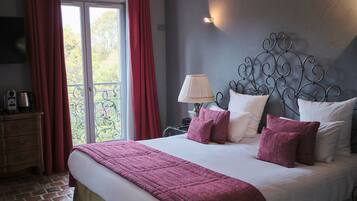 A bedroom with a large bed, a wooden headboard, a nightstand with a lamp, and a view of the outdoors through a sliding glass door.